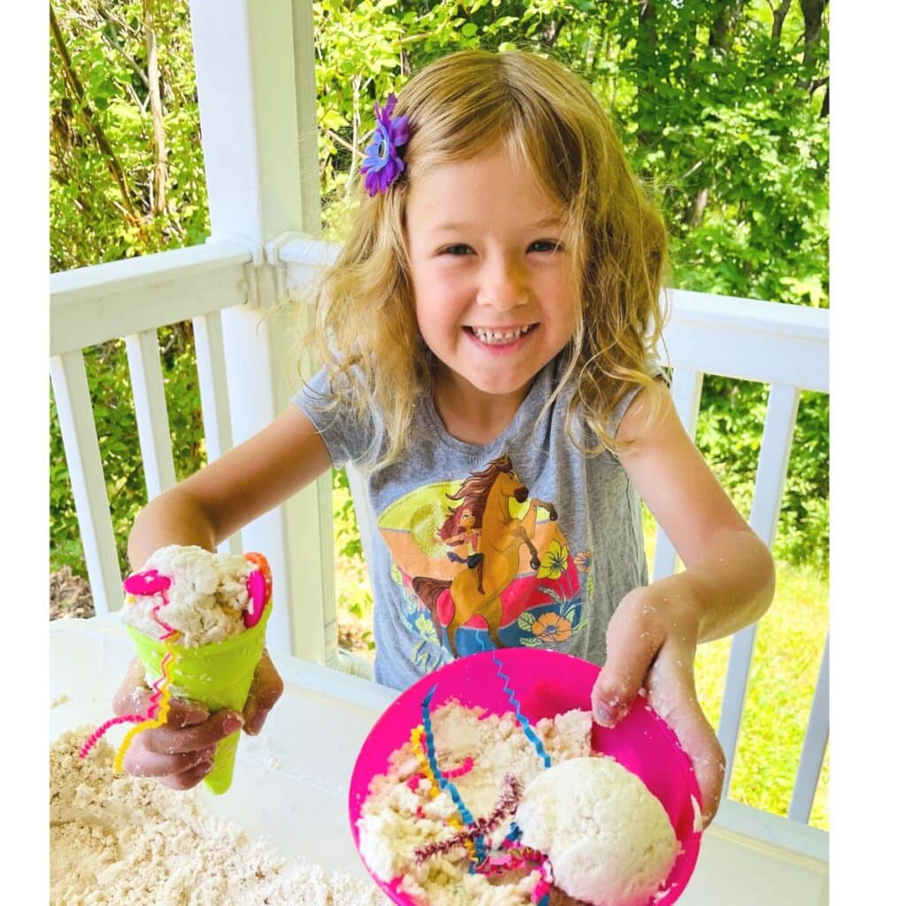 child serving up an ice cream cone and an ice cream sundae in this summer sensory bin idea