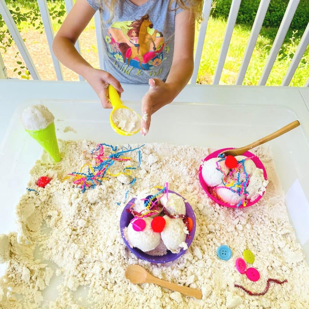 child packing down moon sand into an ice cream scoop