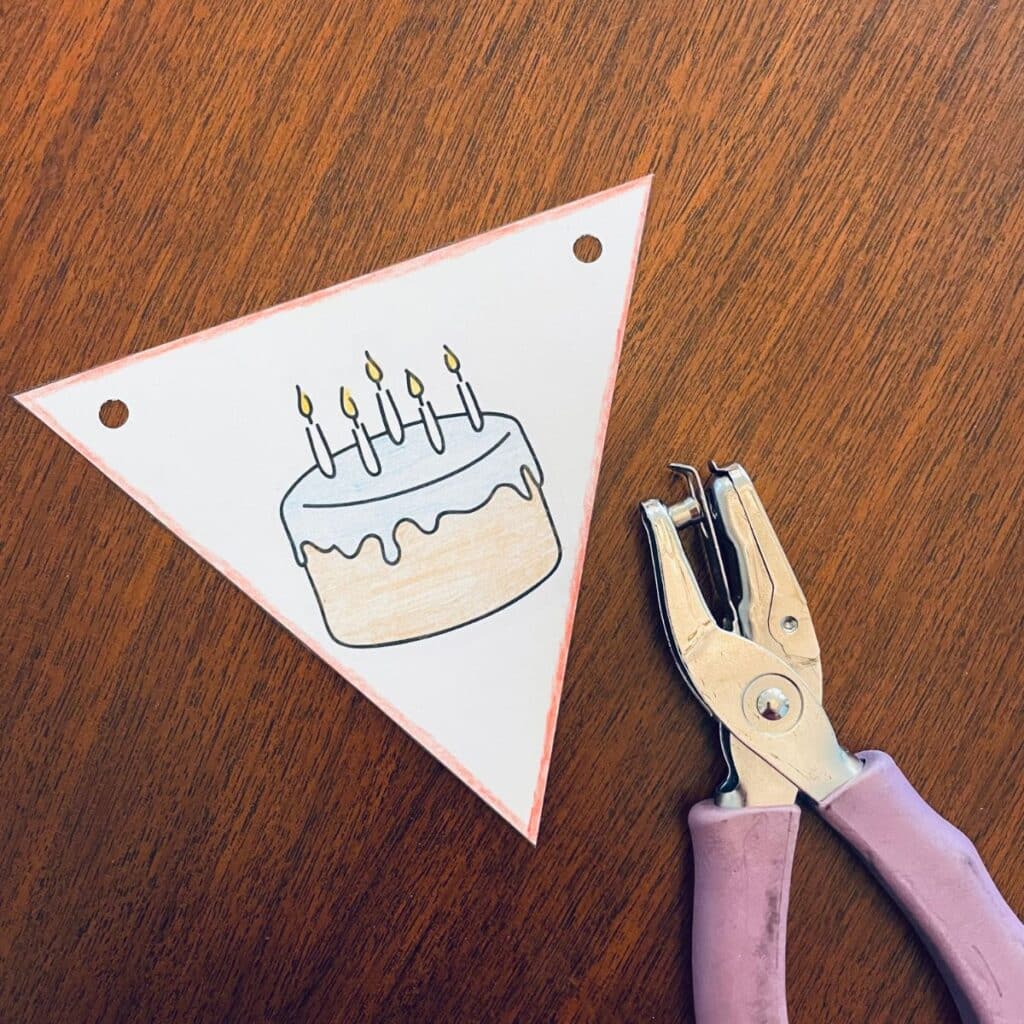 hole punching the birthday banner pieces