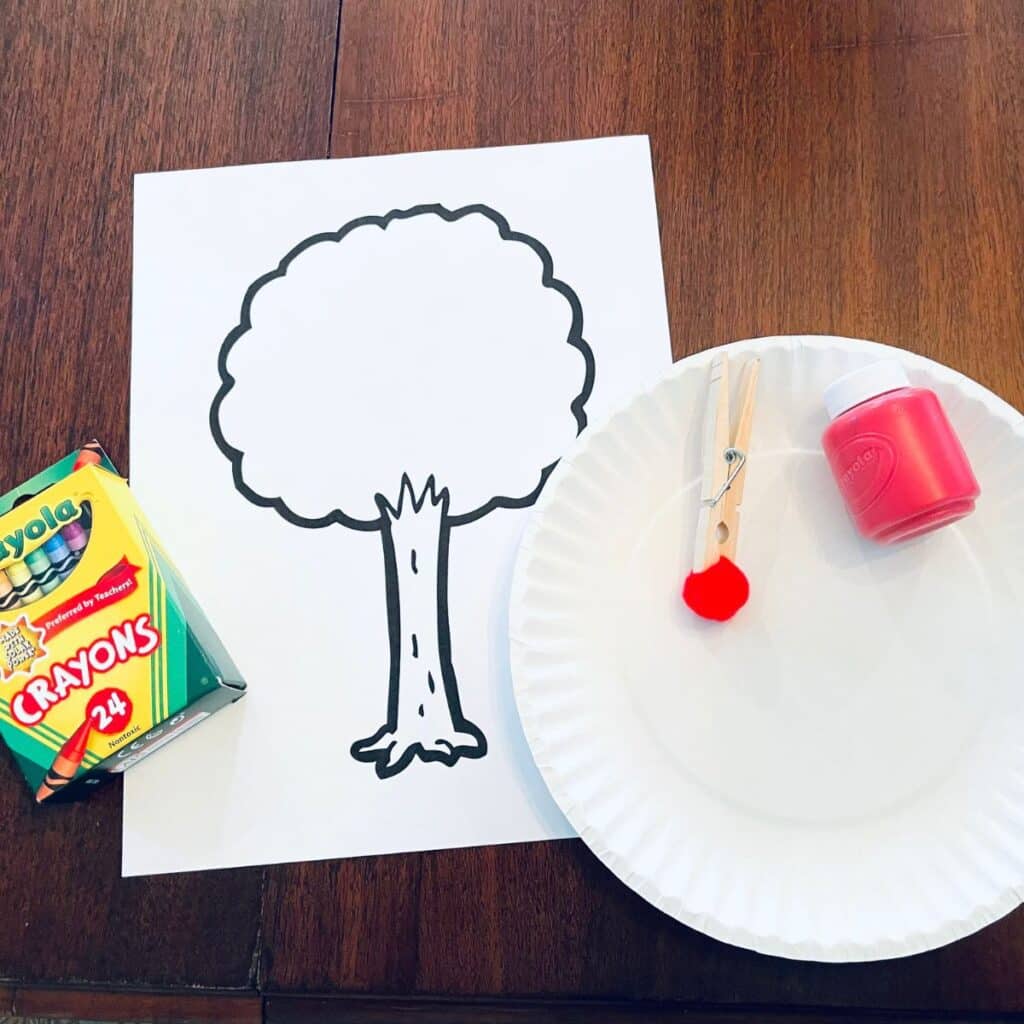 supplies for apple tree craft including crayons, red paint, pom pom clothespin, paper plate and apple tree template