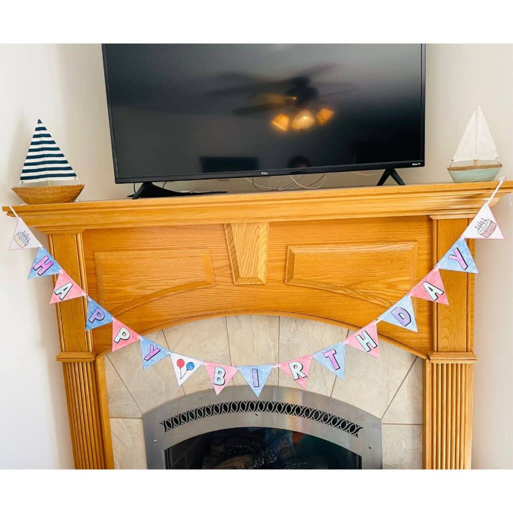 happy birthday banner - color your own banner free printable hung up on a mantle