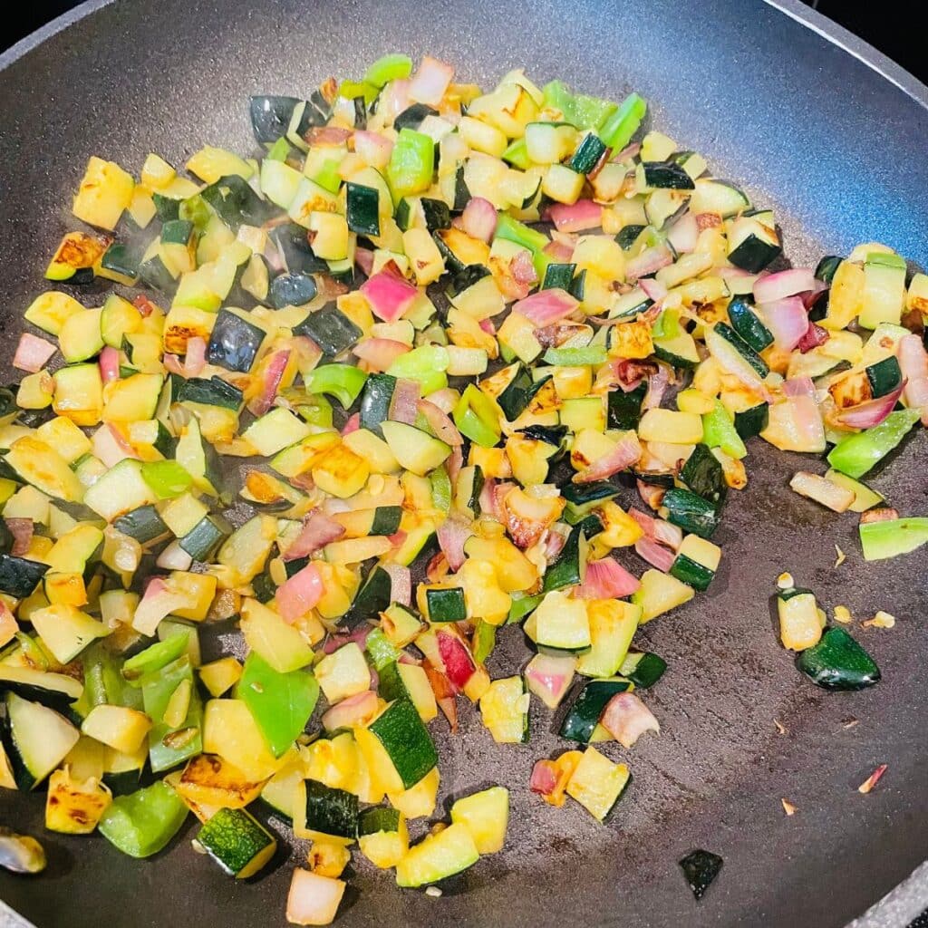 zucchini sauteed in a skillet with onions and peppers