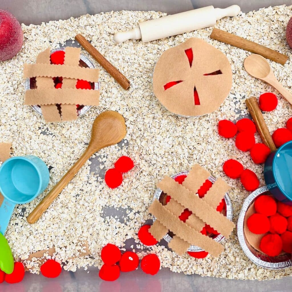 apple pie sensory bin with felt pie crusts, oats, pom poms and scooping tools