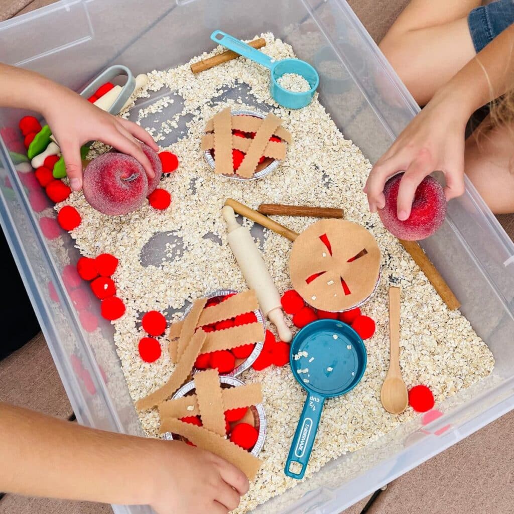 2 children playing with apple pie sensory tub