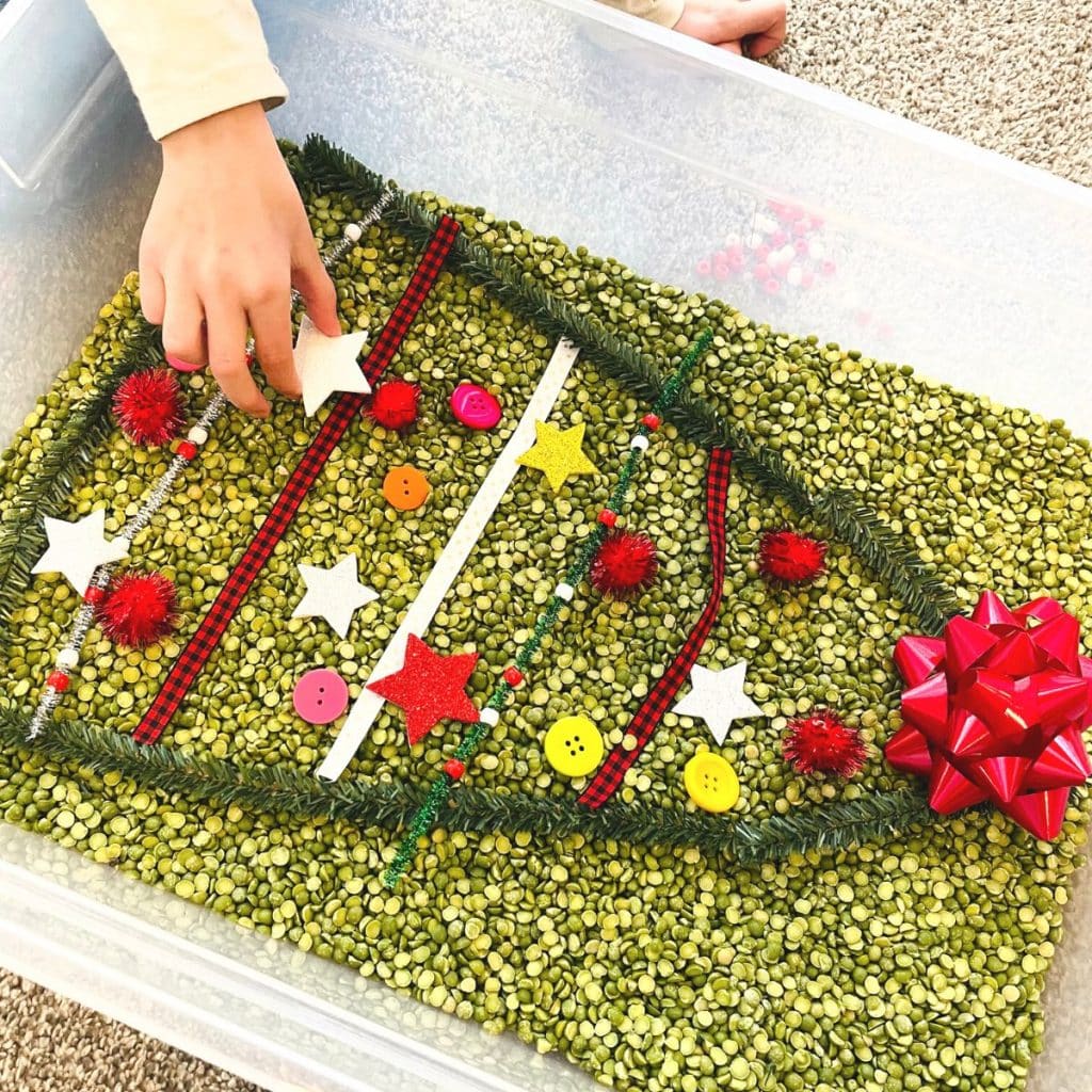 Child adds stars to a Christmas tree sensory bin