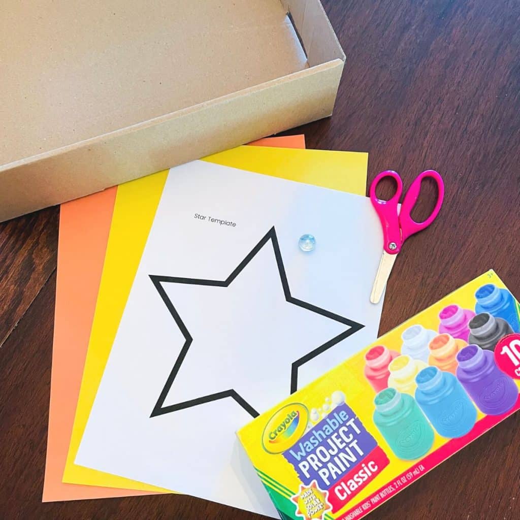 Preschool star craft supplies including a shallow box, scissors, star template, construction paper, marble, and washable paint