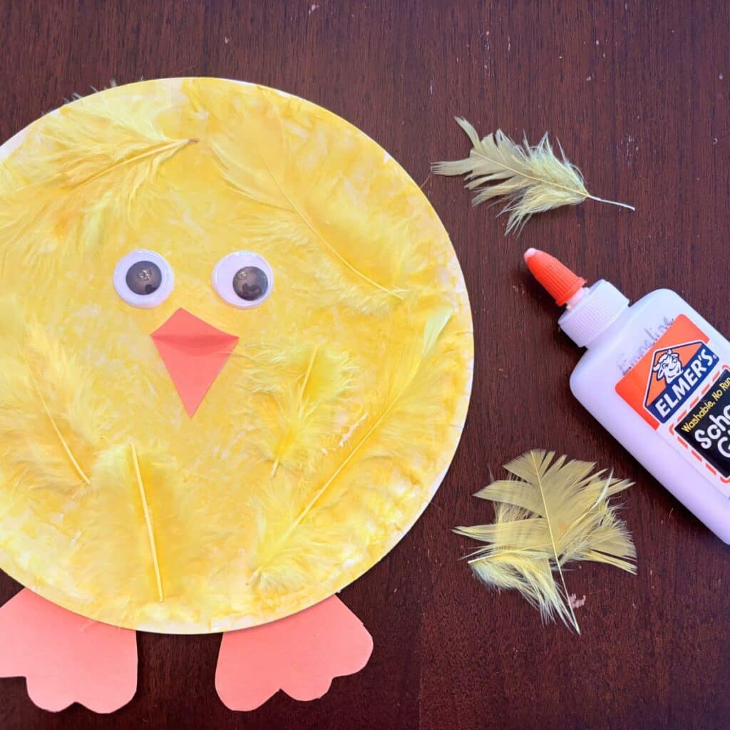 adding yellow feathers to the paper plate chick craft