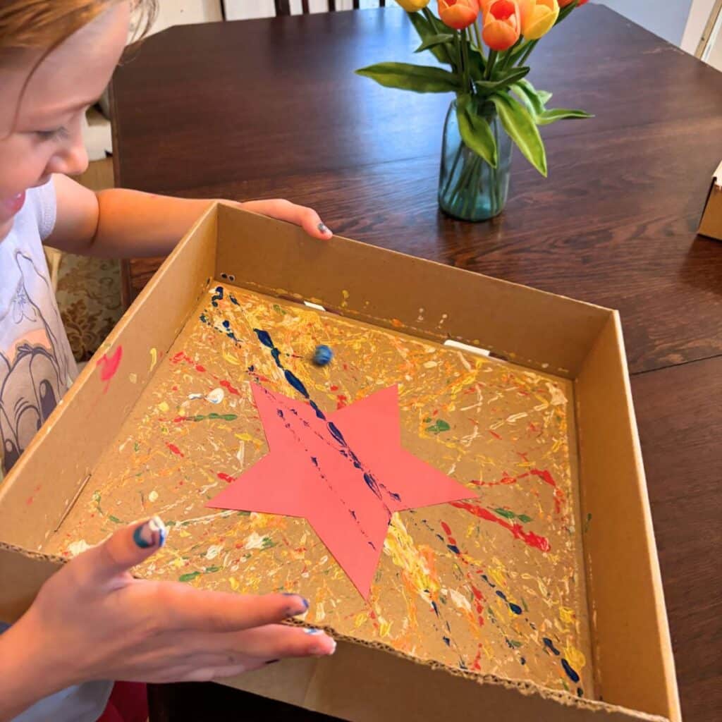 child moving the box to marble paint a star